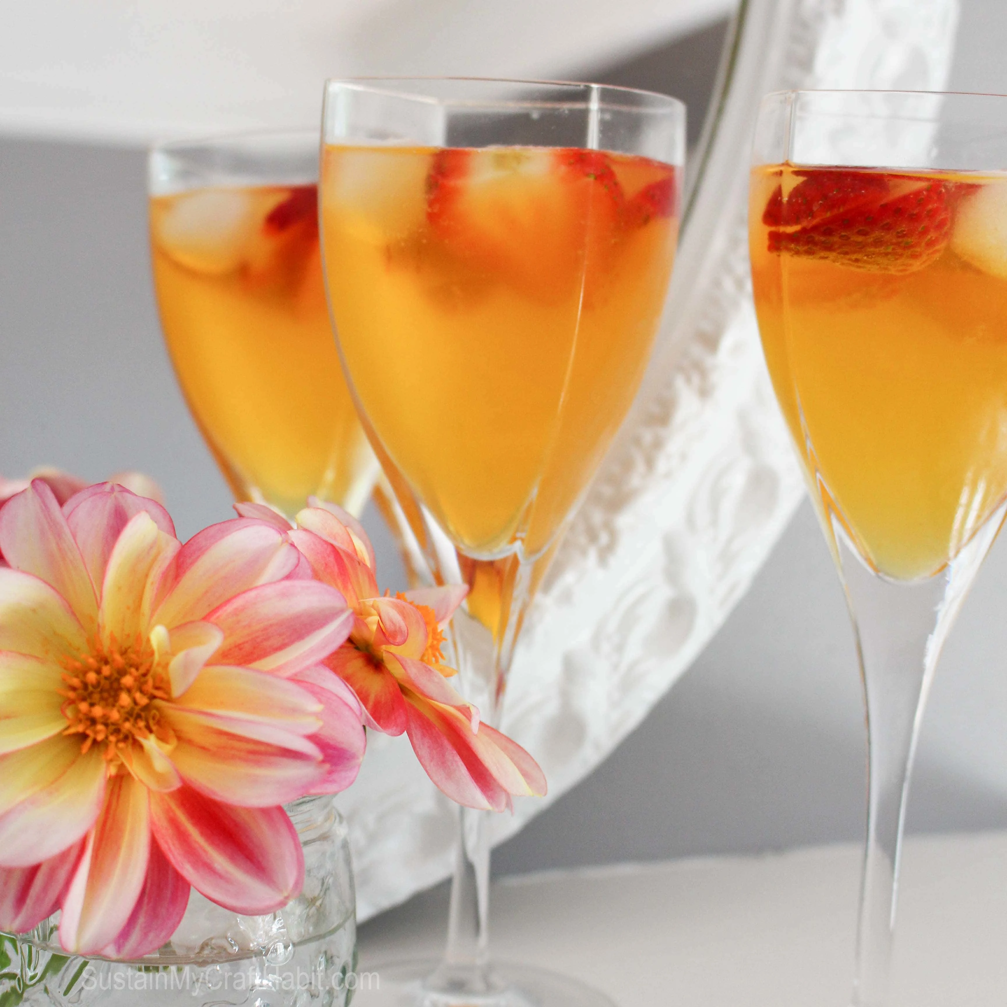 A stemmed wine glass filled with the peach belini and garnished with fresh strawberry slices