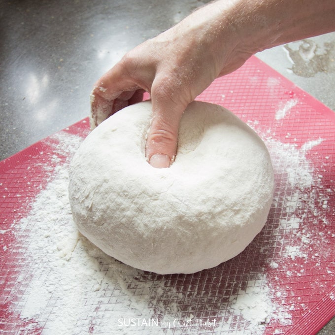 Woman demonstrating when the bread dough has been kneaded enough by placing a thumb in the center to test for firmness