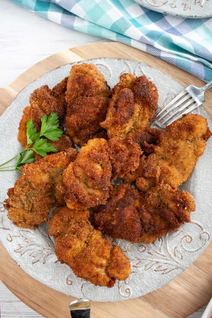 Strips of fried chicken coated with breadcrumbs on a white plate.