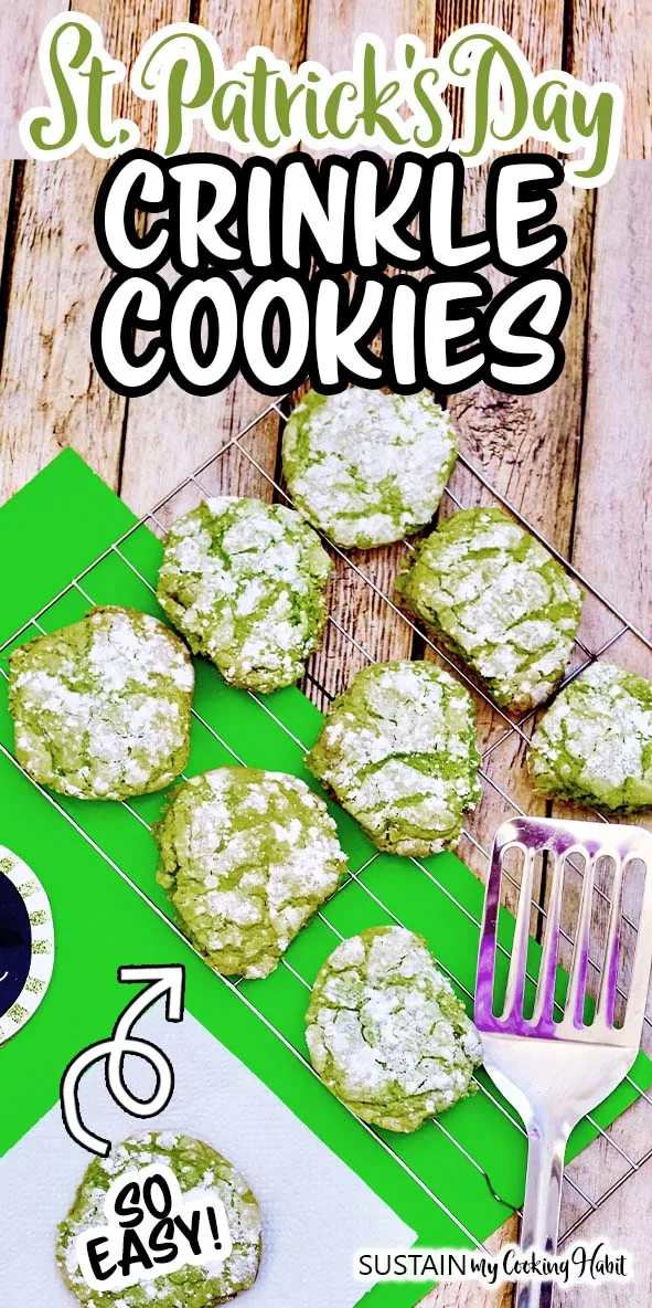 A batch of green crinkle cookies on a cooling rack on a bright green place mat and rustic wood surface.  A silver spatula rests on the side and text overlay reads St. Patrick's Day Crinkle Cookies.
