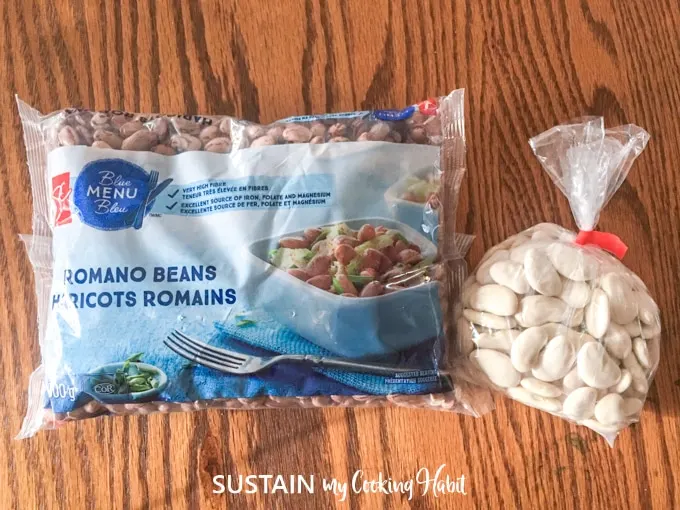 Two bags filled with dried romano beans and dried white lima beans on a wood surface.
