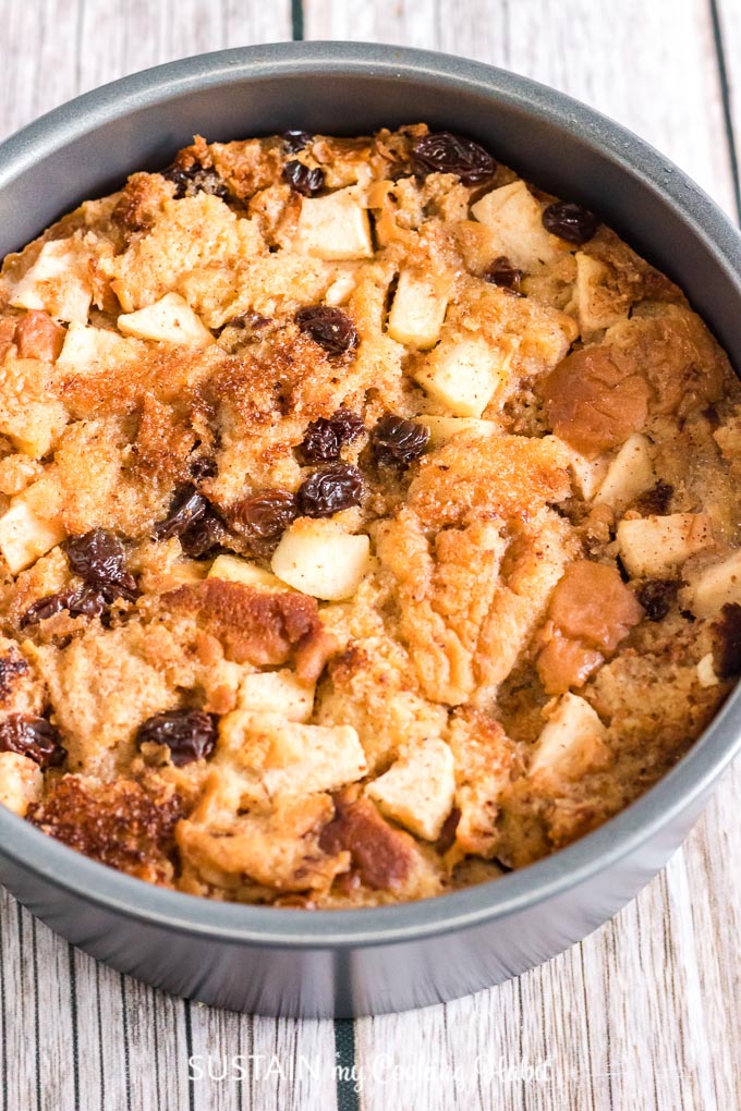 Close up image of the baked apple bread pudding in a round grey baking pan after it came out of the Instant Pot.