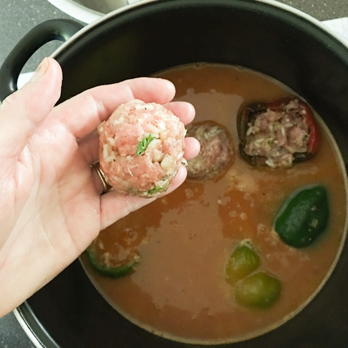 Placing a meatball into the pot.
