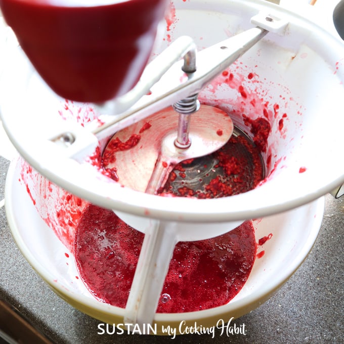Using a hand mill to remove seeds and get juice from raspberries.