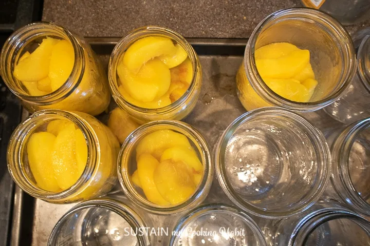 Filling mason jars with cooked peaches.