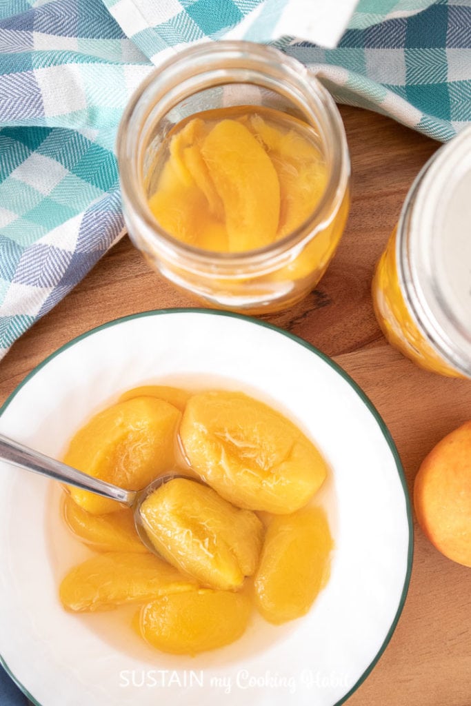 Canned peaches in a jar and in a bowl with spoon.