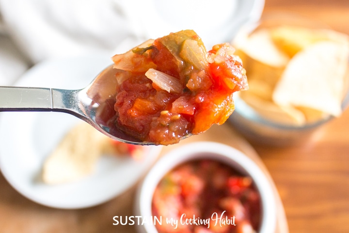 Scooping homemade salsa with a spoon.