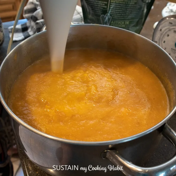 Adding sugar to the blended peaches.