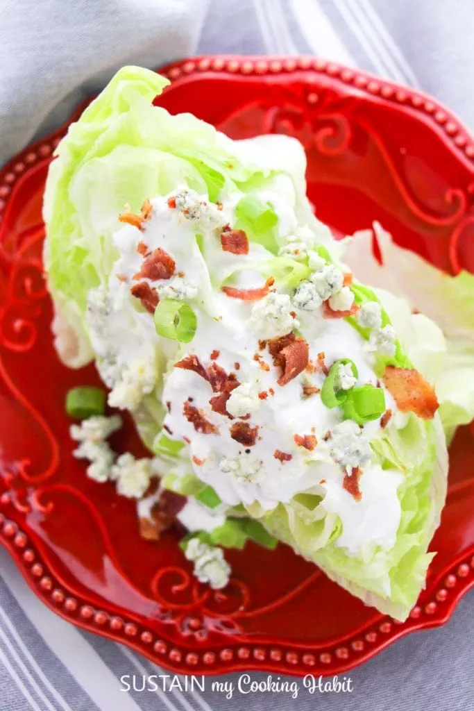 Finished iceburg wedge salad on a red plate.