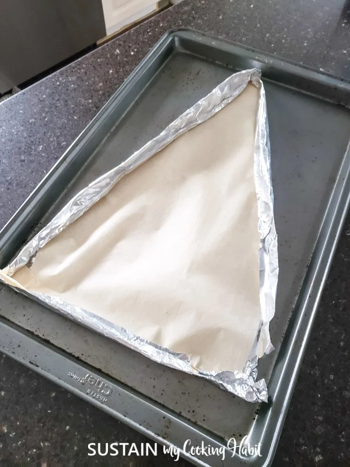 making a christmas tree shaped baking pan using a baking sheet, aluminum foil and parchment paper.