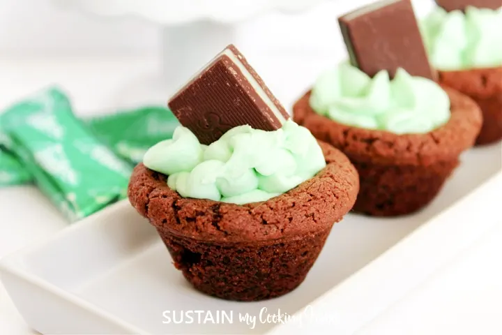 Chocolate mint cookie cup with green frosting and a square of chocolate on top.