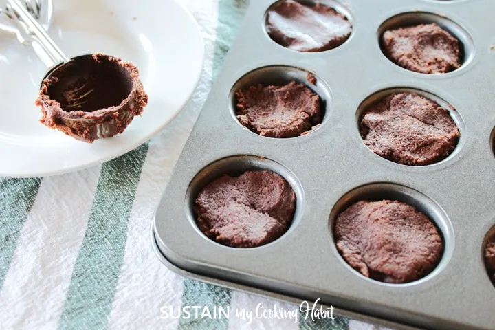 Scooping chocolate cookie dough into muffin pan.