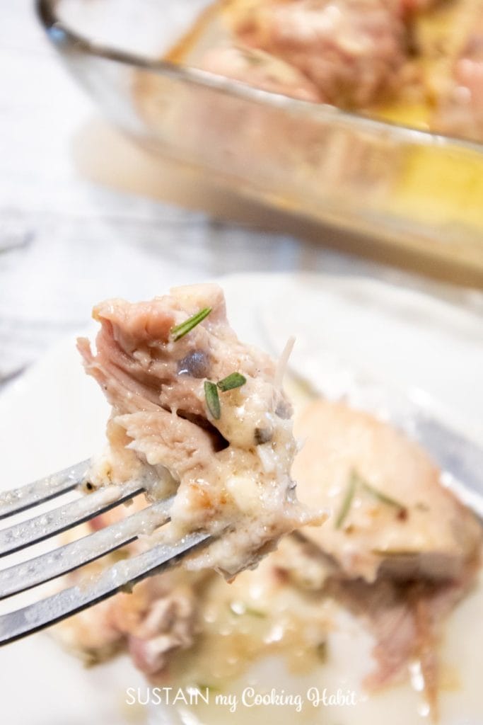 A piece of rosemary chicken thigh on a fork.