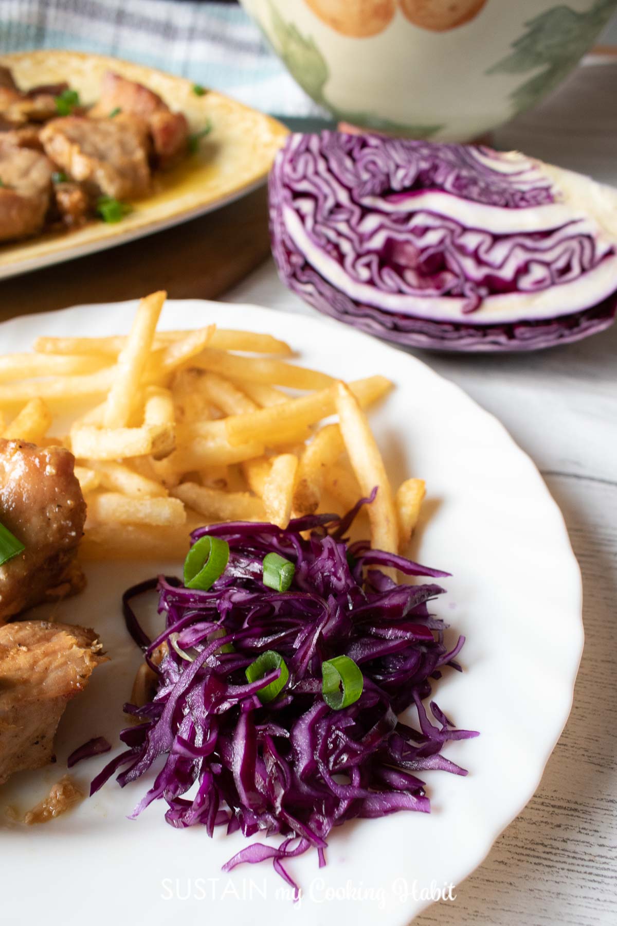 Red cabbage coleslaw served on a plate with chicken and french fries.