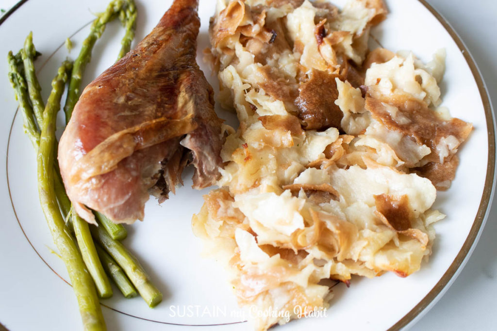 Croatian mlince baked noodles next to a piece of Turkey and asparagus.