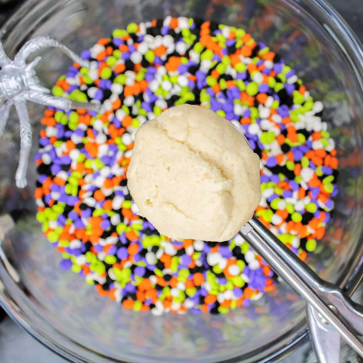 Adding a scoop of cookie dough into the sprinkles.