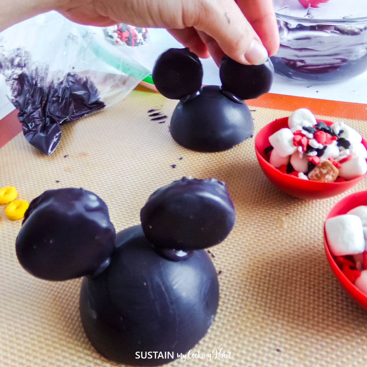 Attaching peppermint patties to the black cups to form ears.
