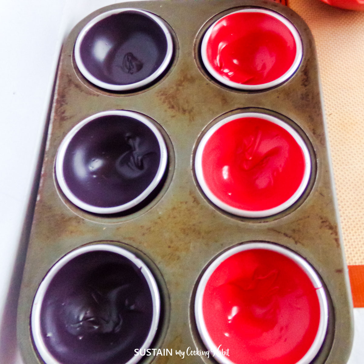 Melted black and red chocolate in a silicone mold.
