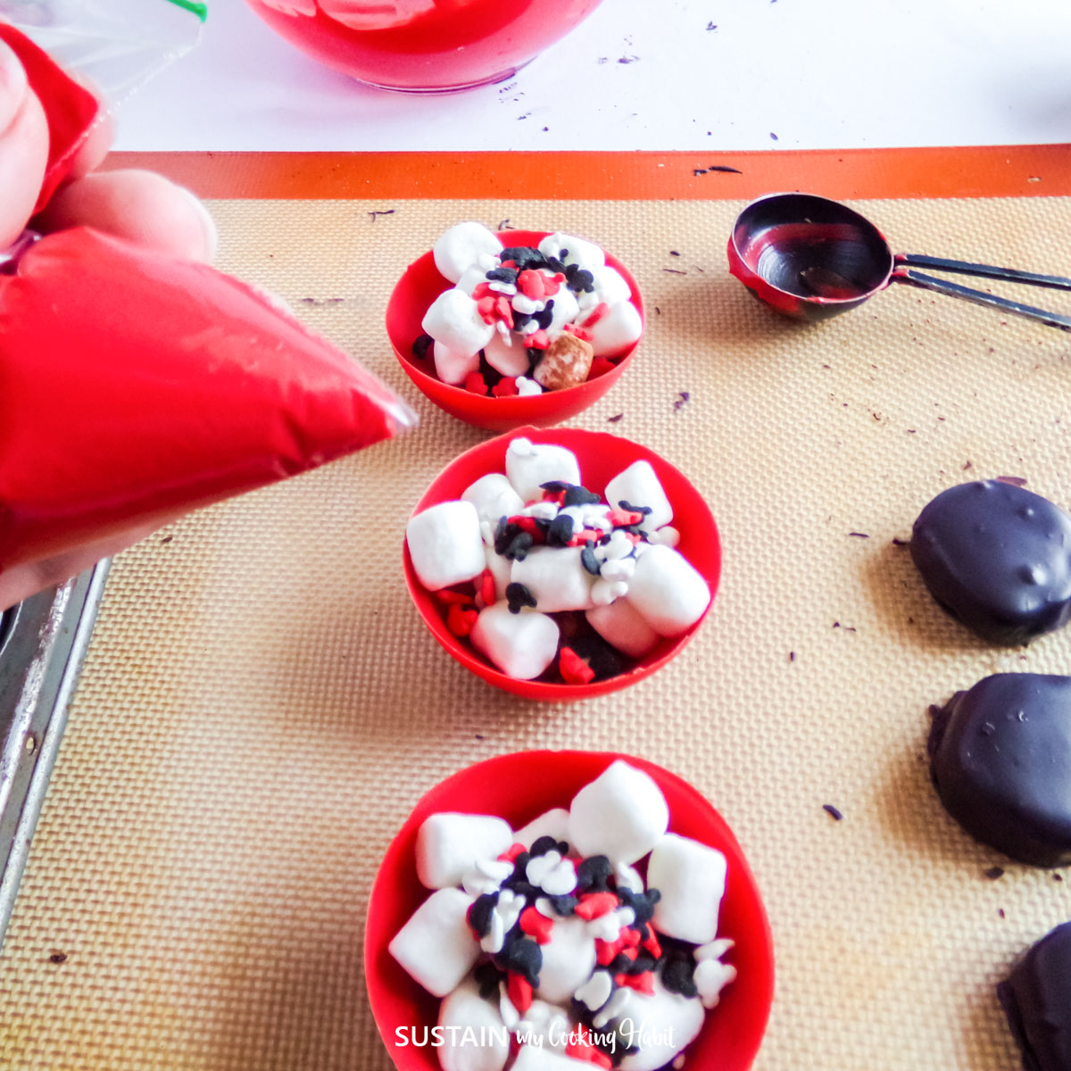 Red chocolate cups filled with mini marshmallows and sprinkles.