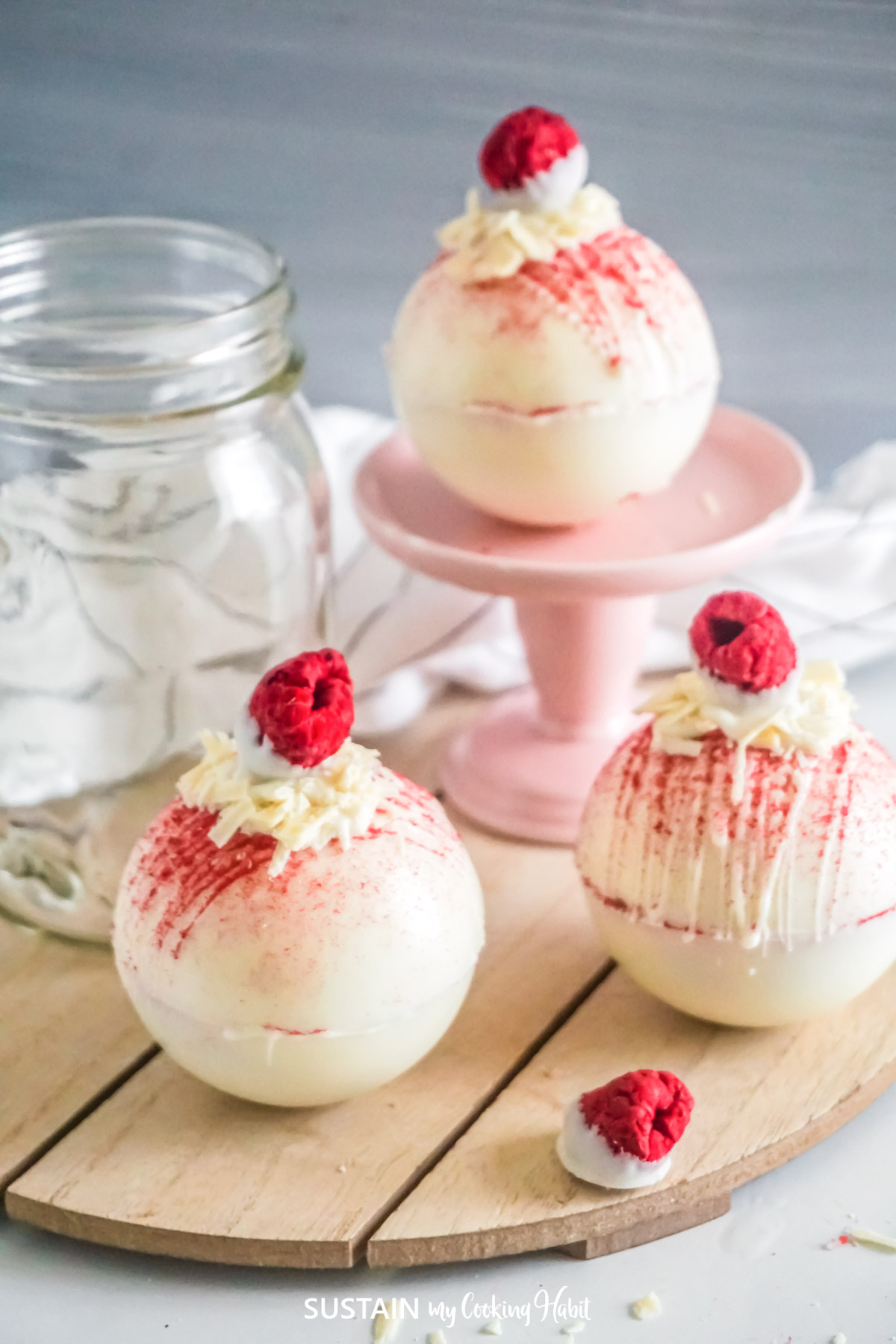 White chocolate raspberry hot cocoa bombs on a platter.