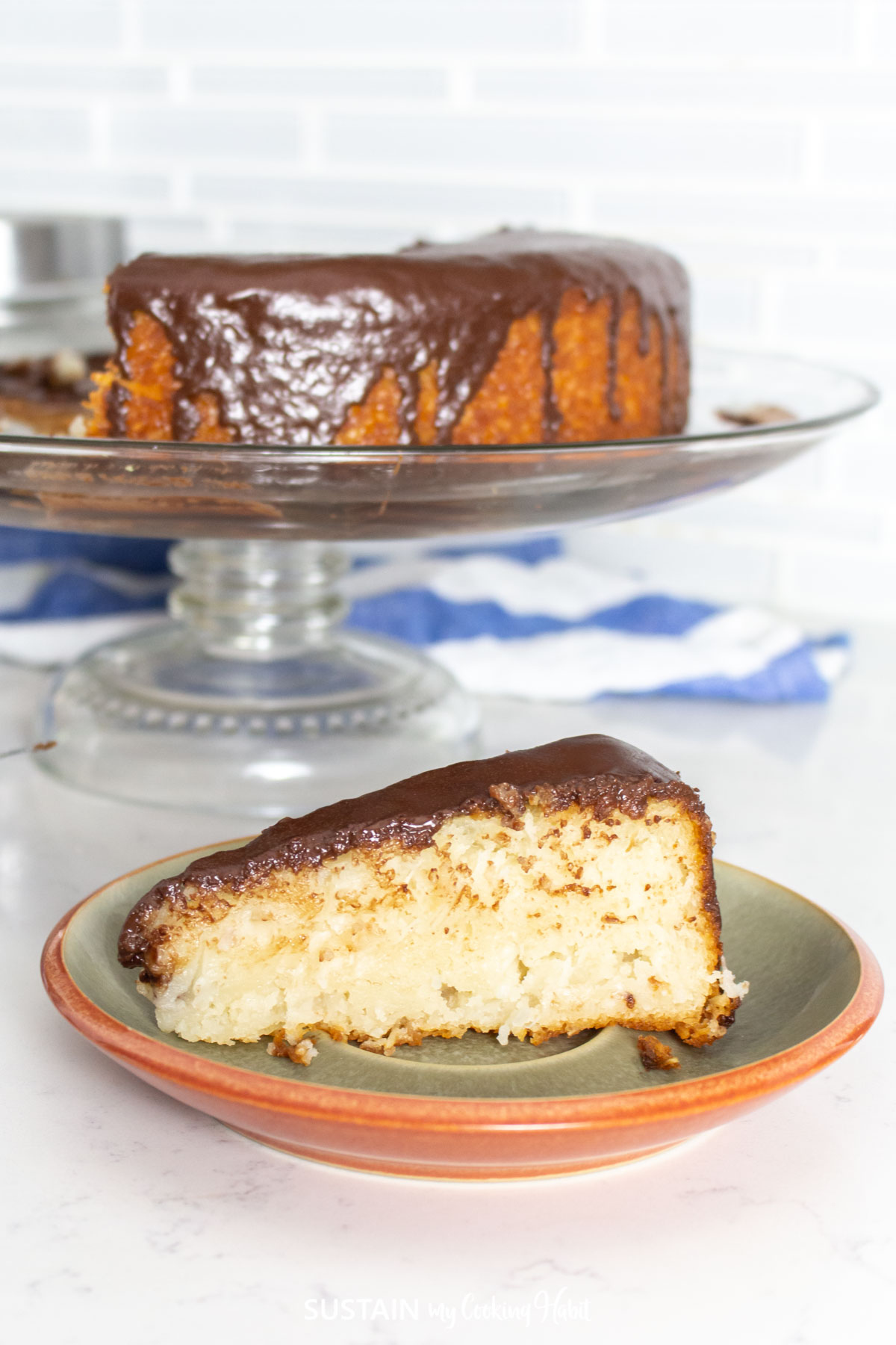A slice of coconut cake with a chocolate glaze topping