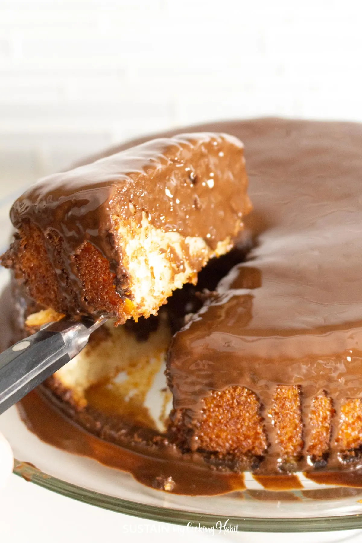Cutting a piece of coconut cake with a chocolate glaze topping