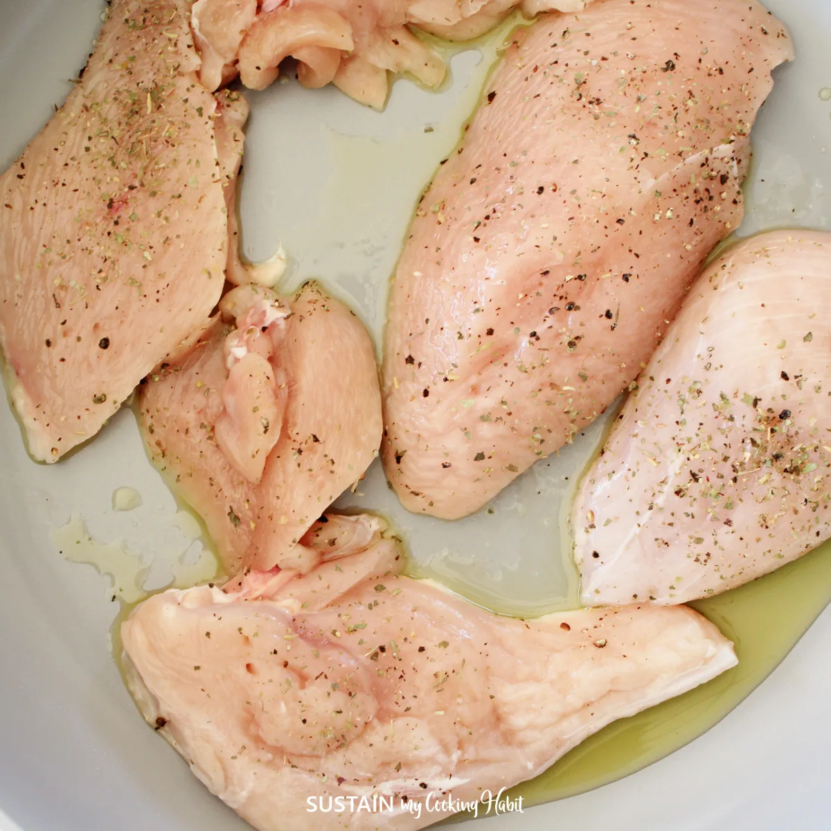 Seasoned chicken breast in a pan.