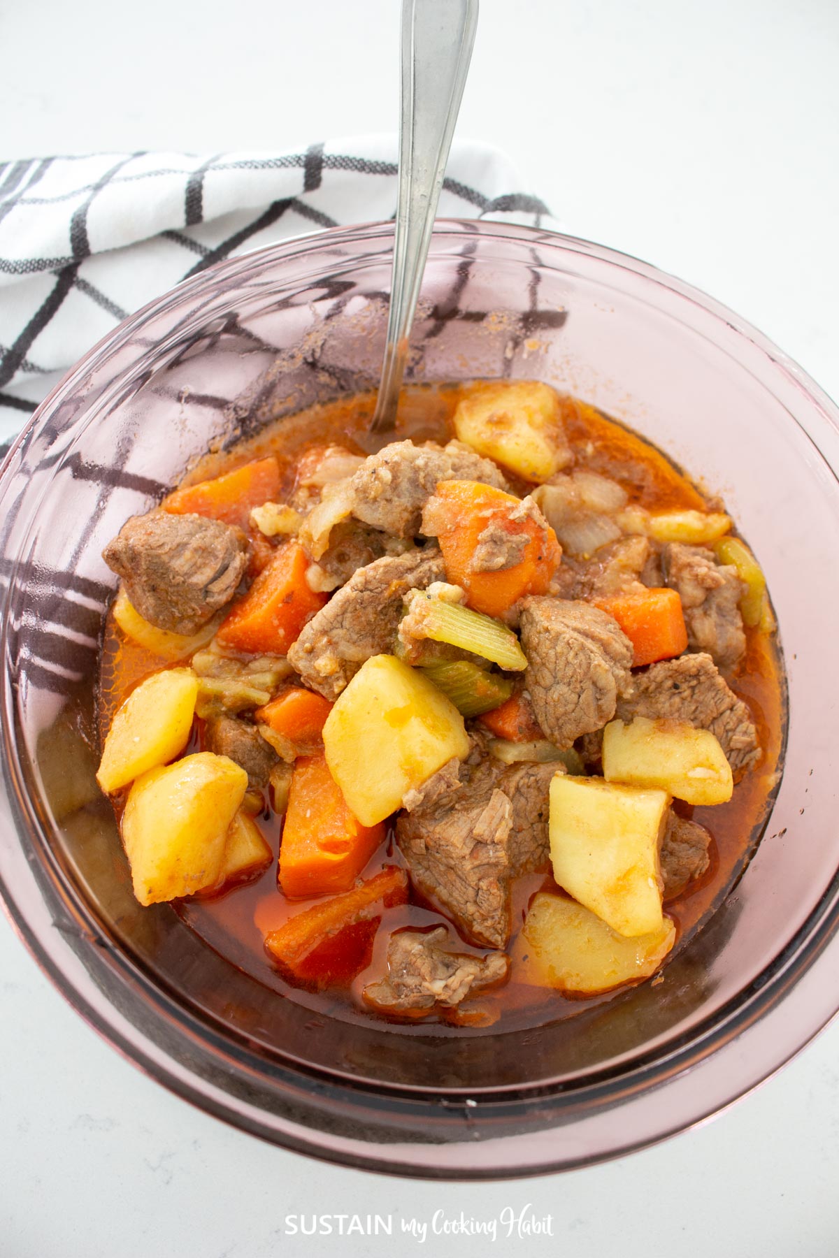 Hearty beef and vegetable goulash in a bowl with a spoon.