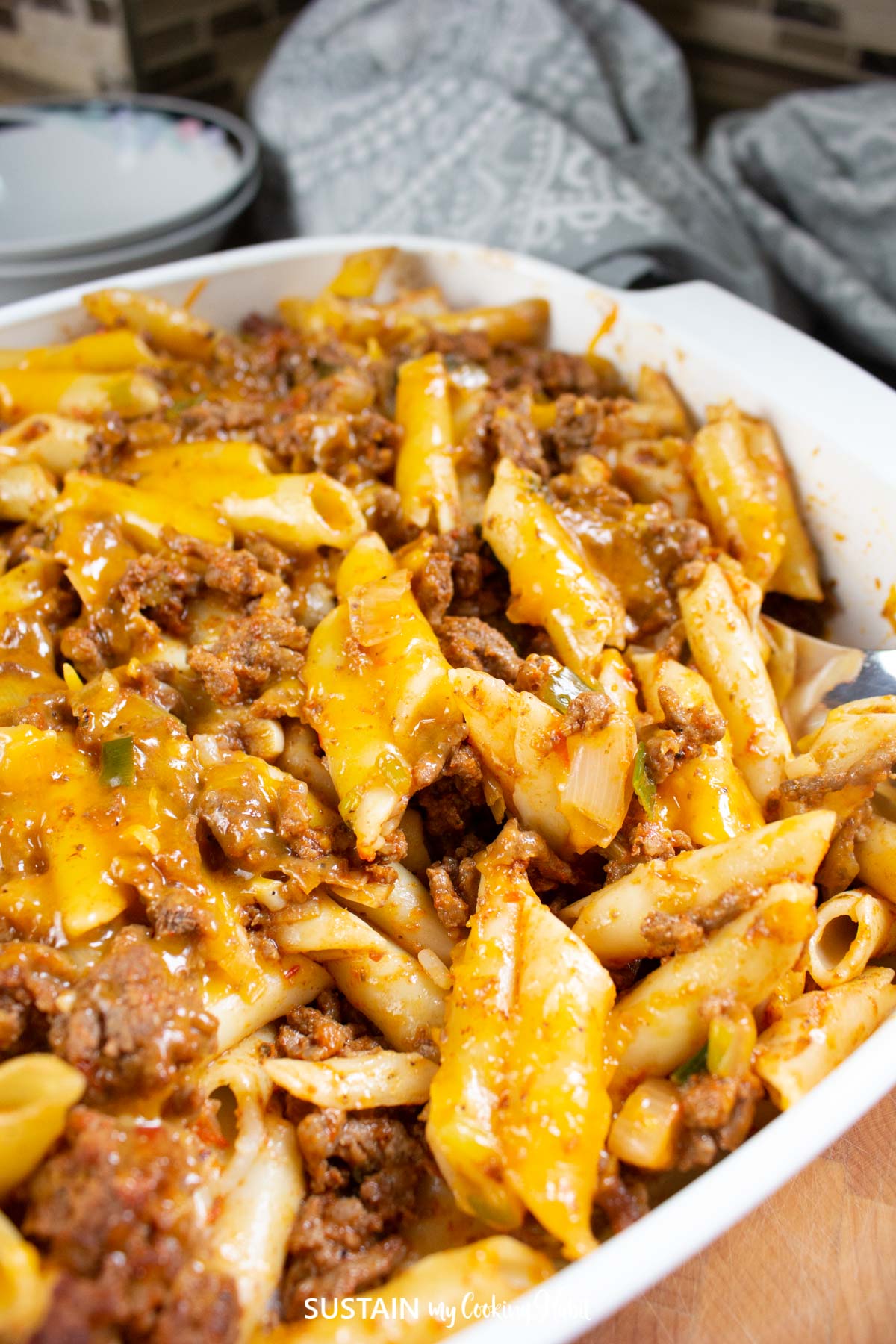 Close up of baked penne pasta with ground beef in a dish.