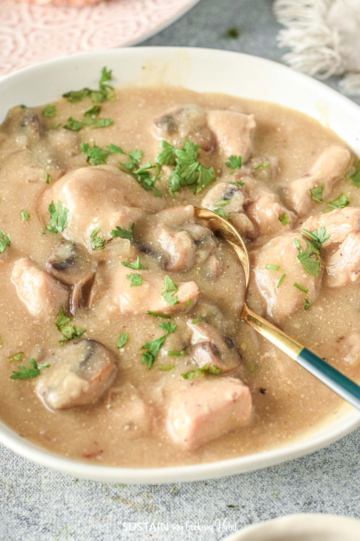 Creamy chicken stroganoff being scooped by a spoon.