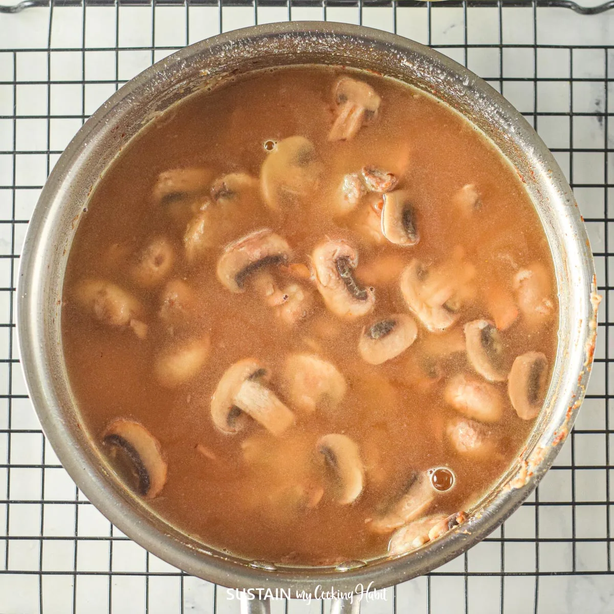 Adding broth to the mushrooms.