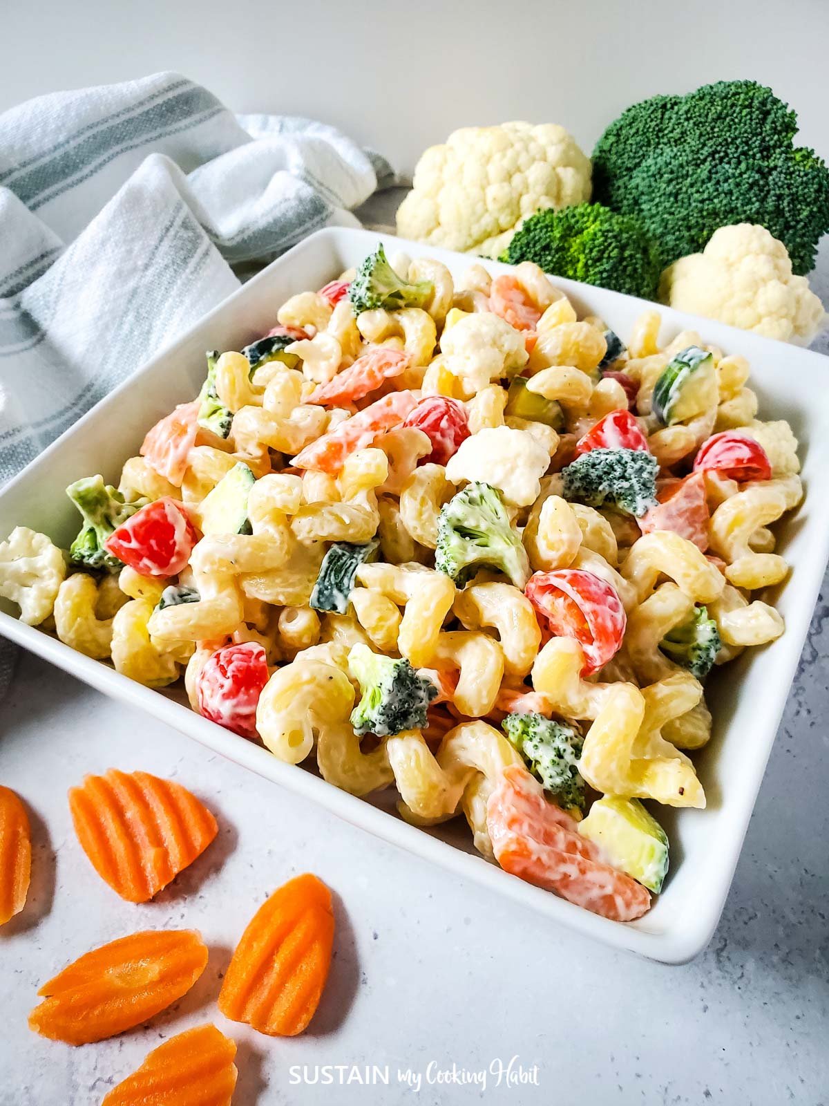 Creamy pasta salad loaded with veggies in a serving dish.