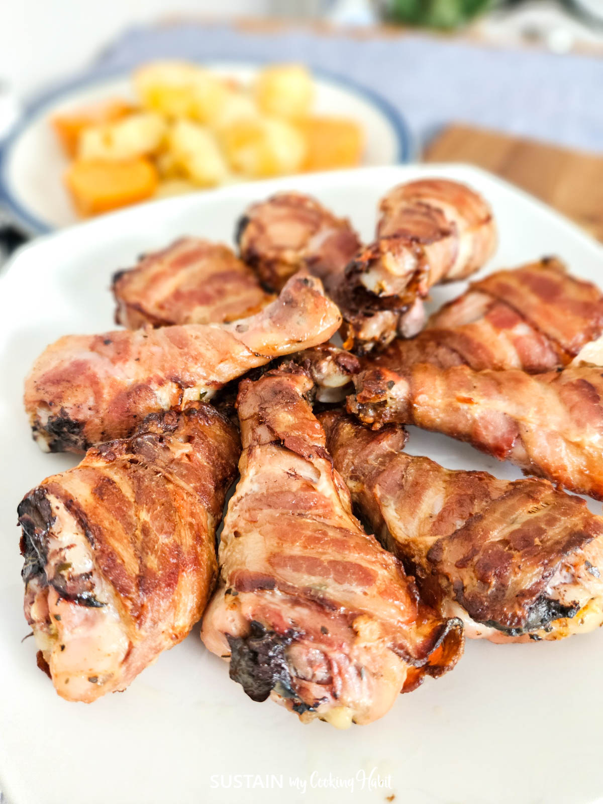 Bacon wrapped drumsticks on a plate.