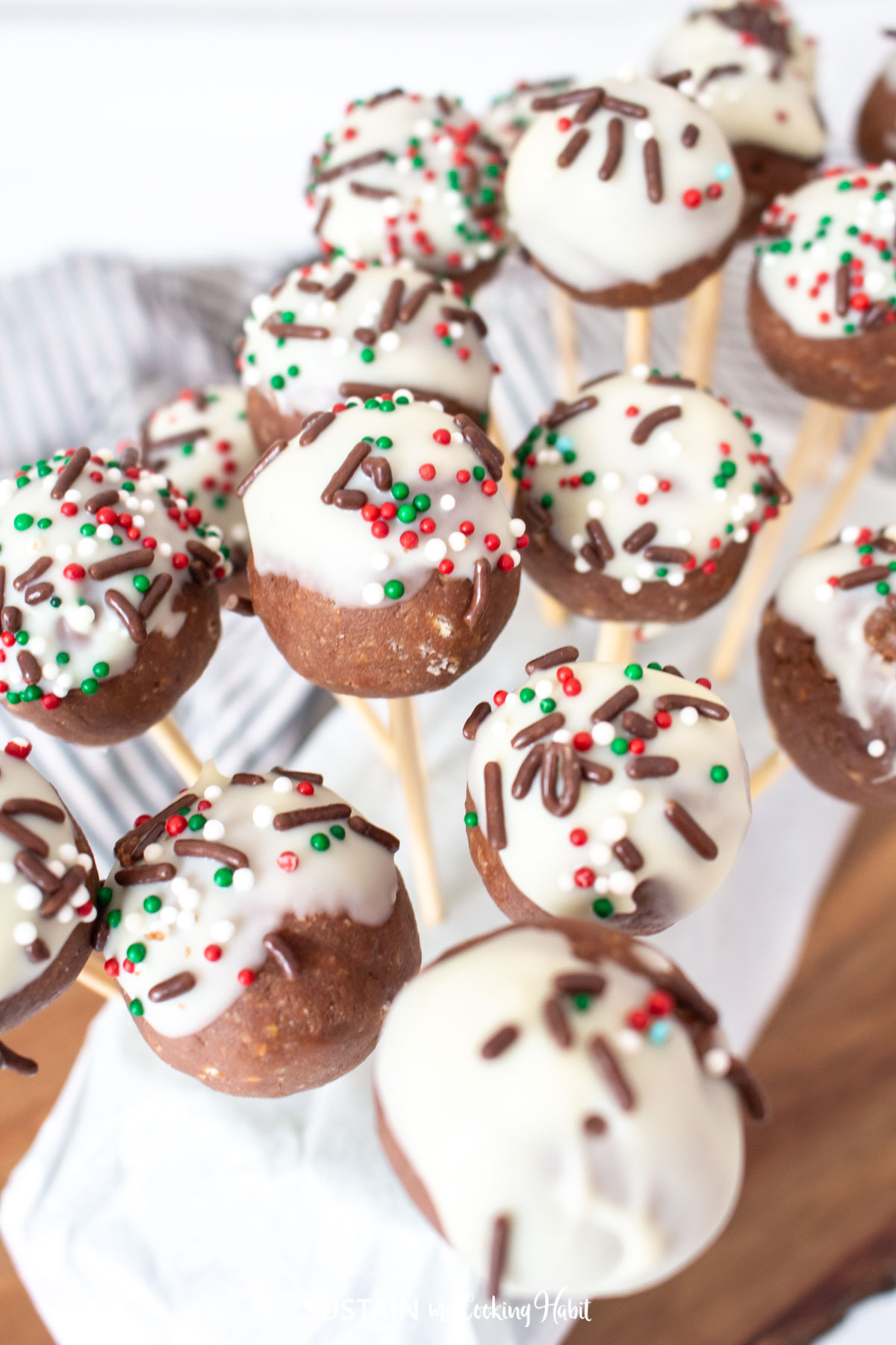 Nutella cake pops with icing and sprinkles on a wood stick.