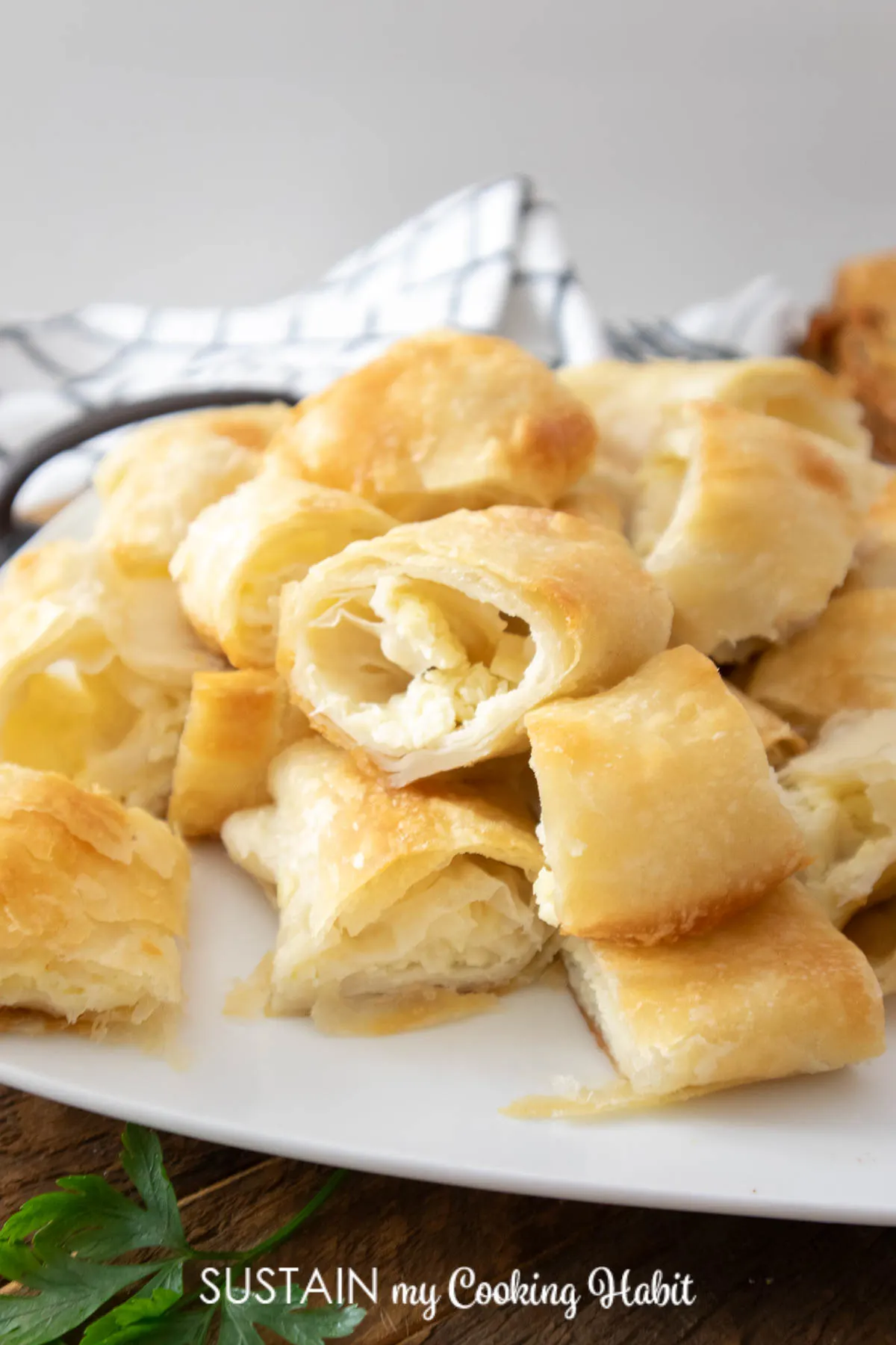 Close up image of cut up pieces of golden cottage cheese strudel pastry on a white platter.