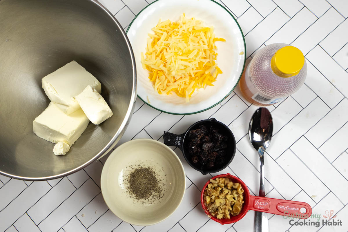 Ingredients needed to make a Cheeseball including cheese, spices, walnuts, cranberries and honey. 