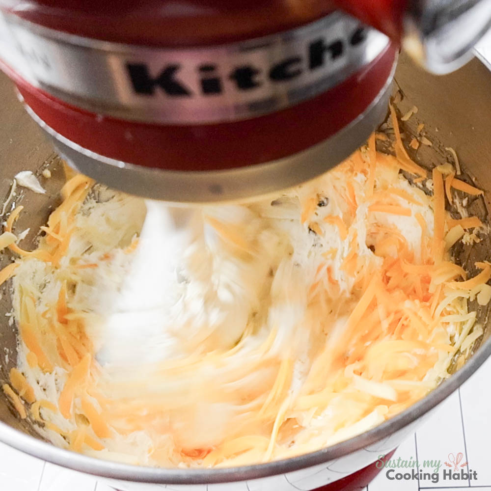 Mixer combining cream cheese and cheddar cheese. 