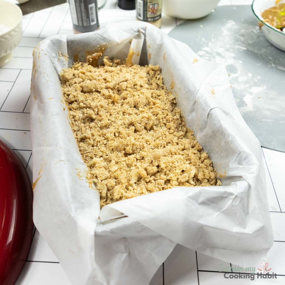Apple cake ingredients inside a parchment lined pan. 
