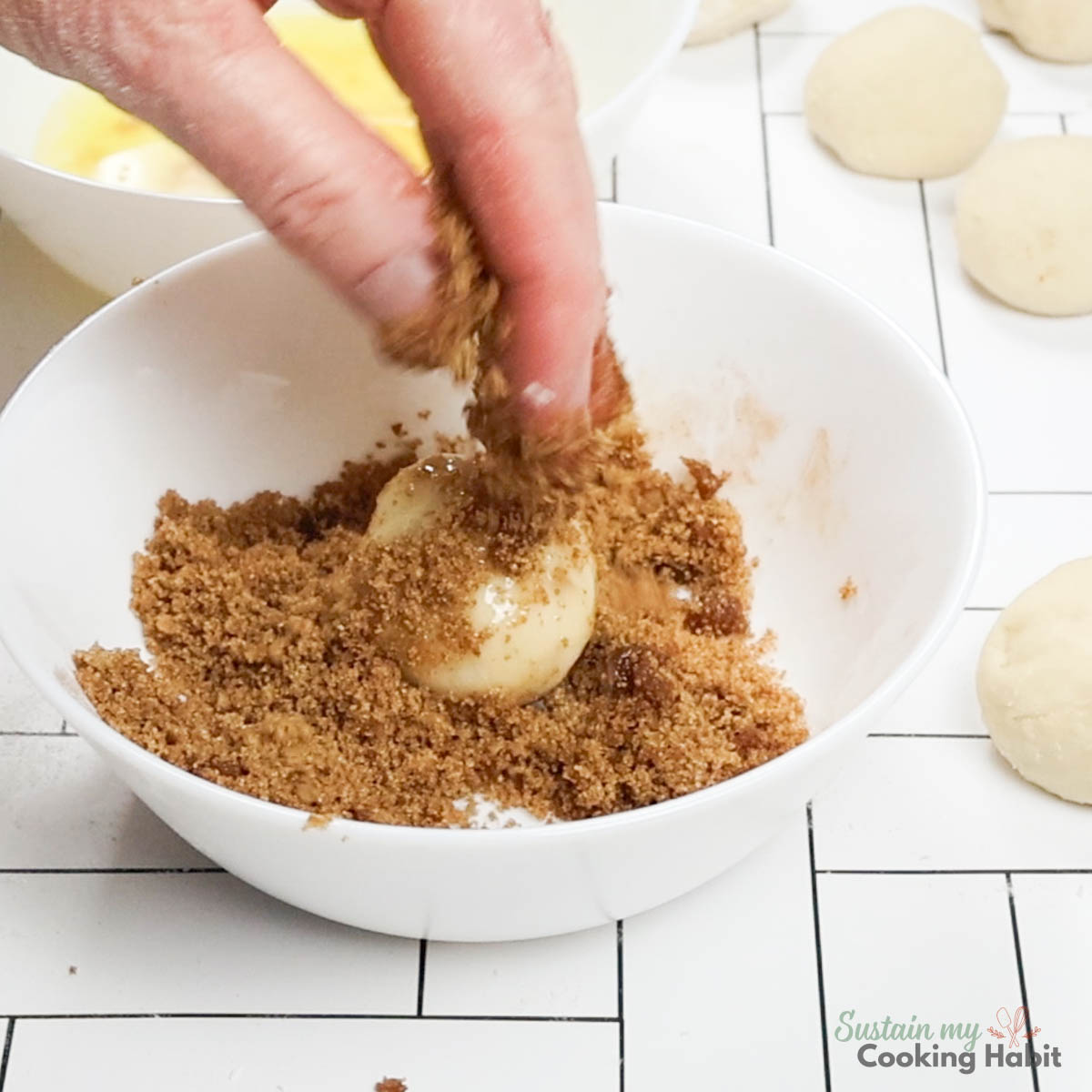 Dipping dough ball into sugar and cinnamon. 