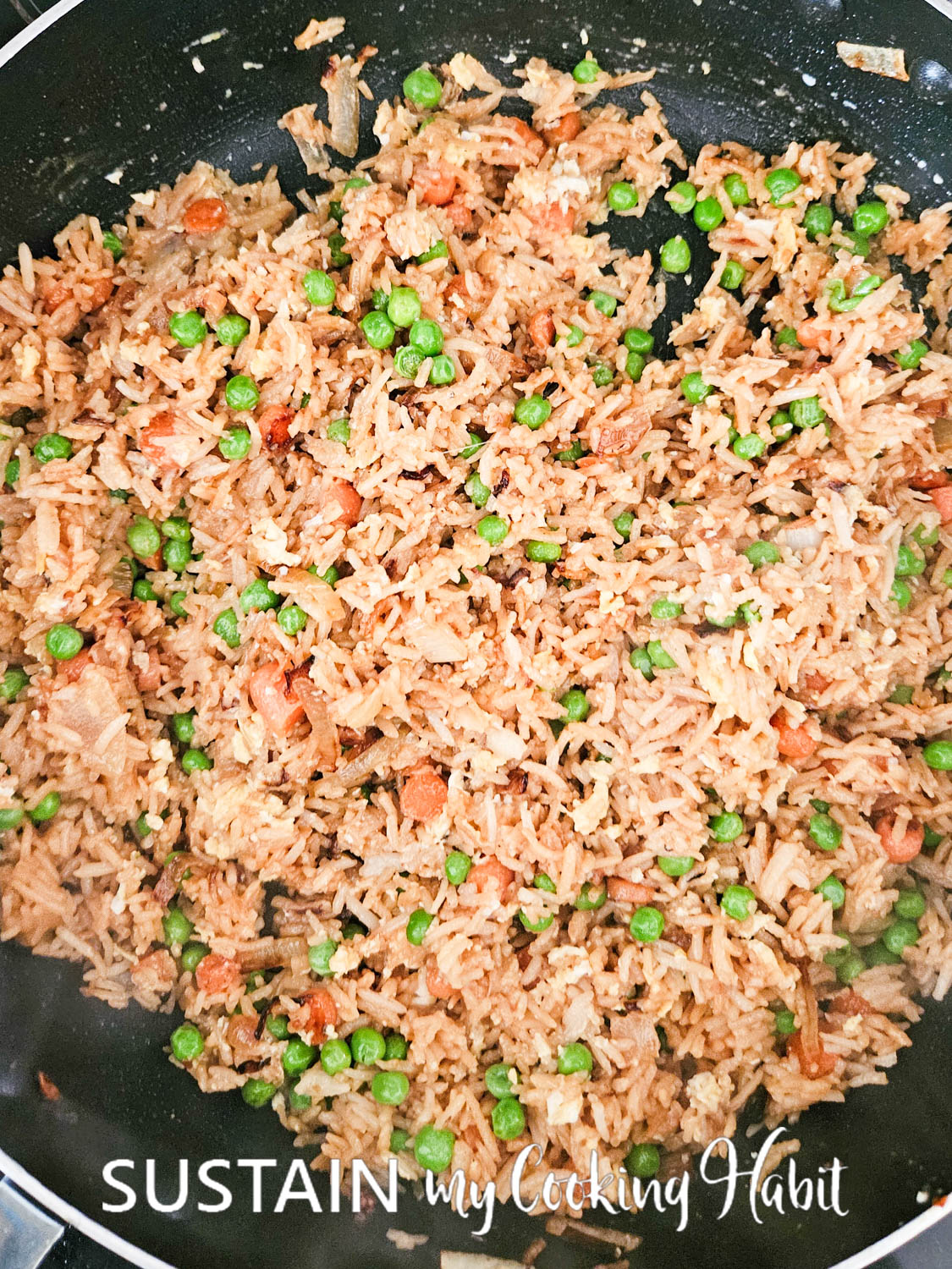 Mixing cooked eggs into vegetable fried rice. 