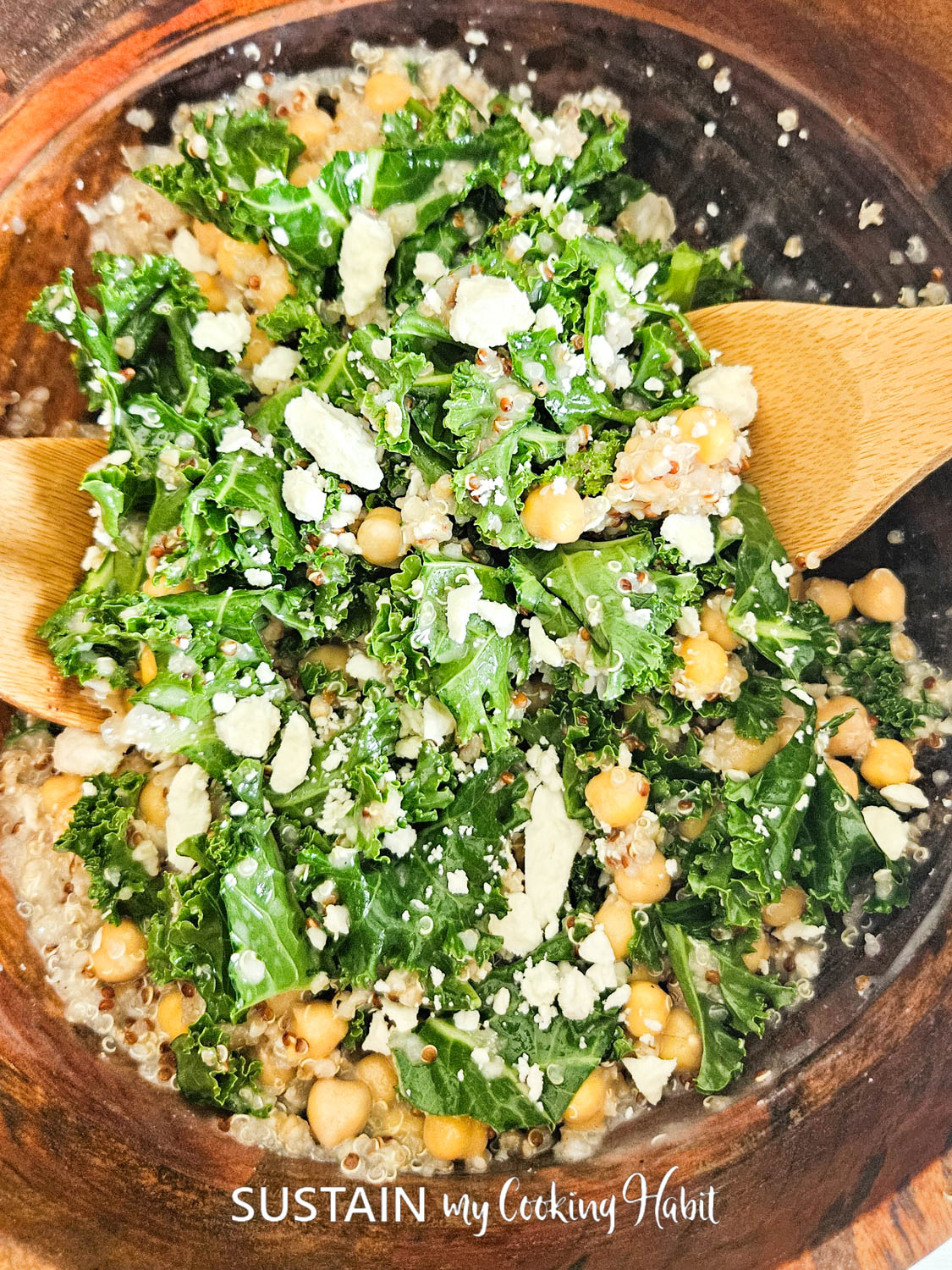 Using wooden spoons to mix kale and chickpea ingredients.