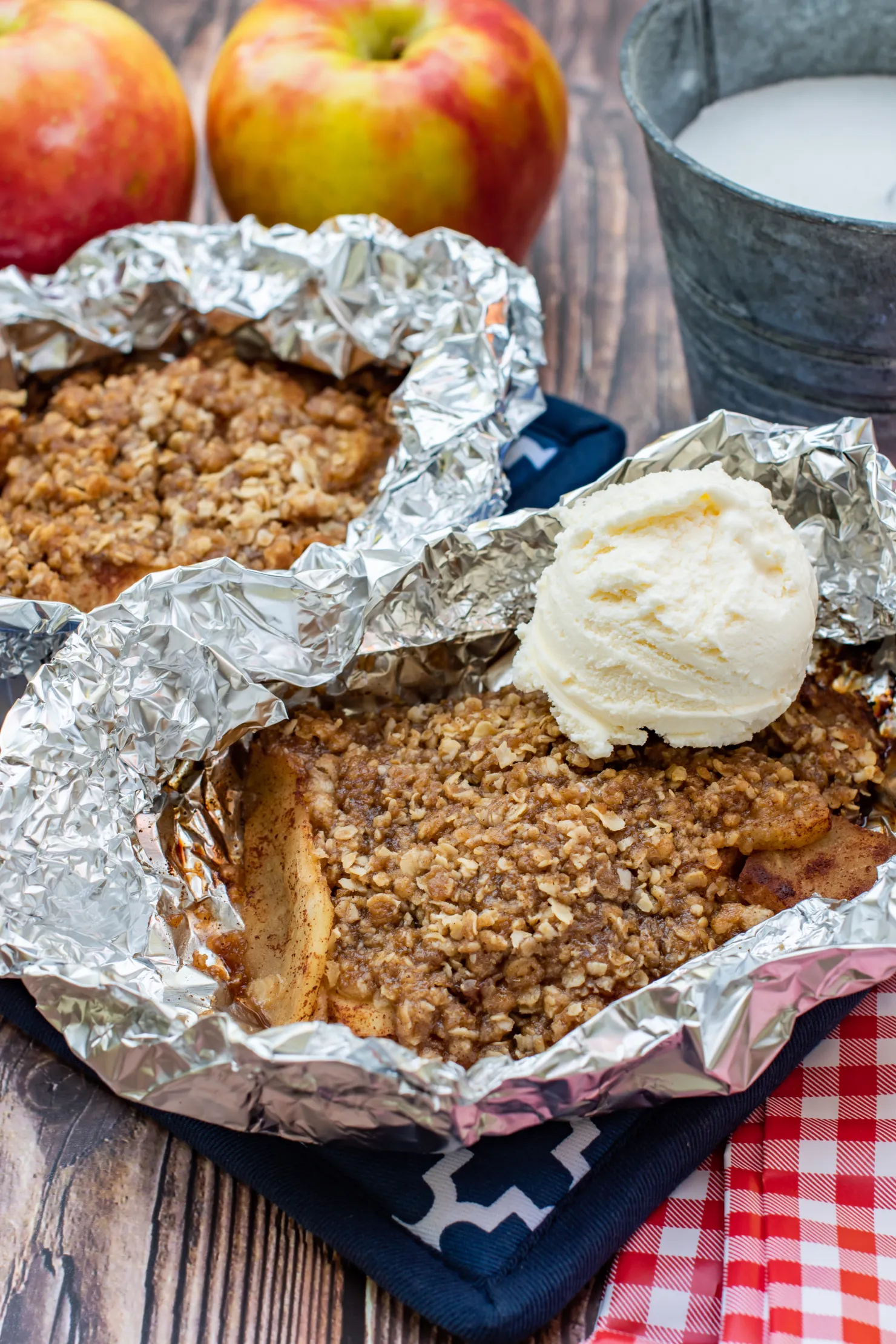 baked apple crisp inside aluminum foil wrap topped with ice cream topping