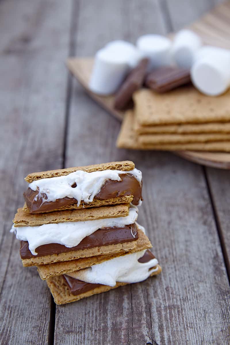 stacked smores treat with melting marshmellows on top of a wooden table