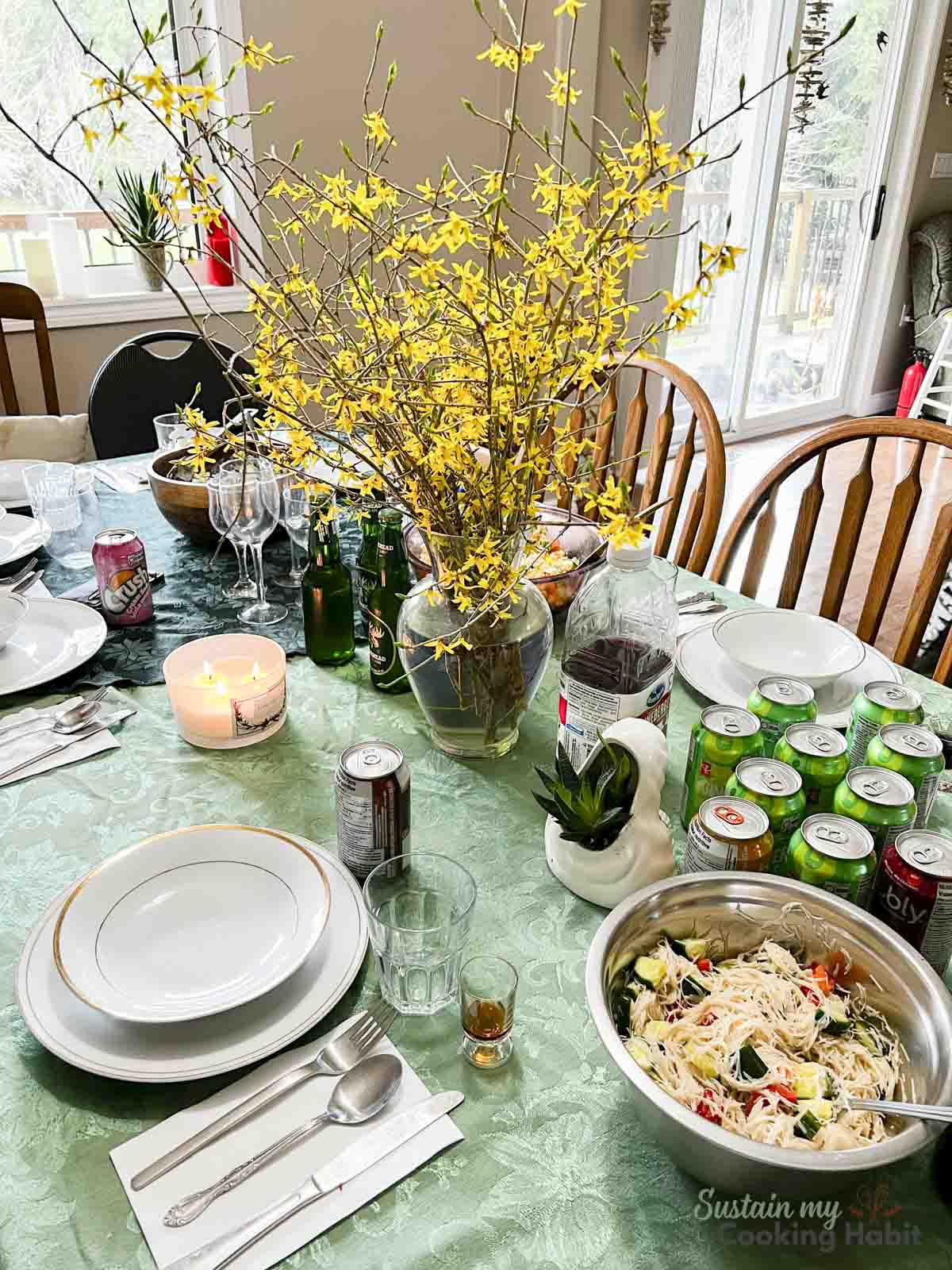 A table set with plates, drinks and a bowl of rice noodle salad.