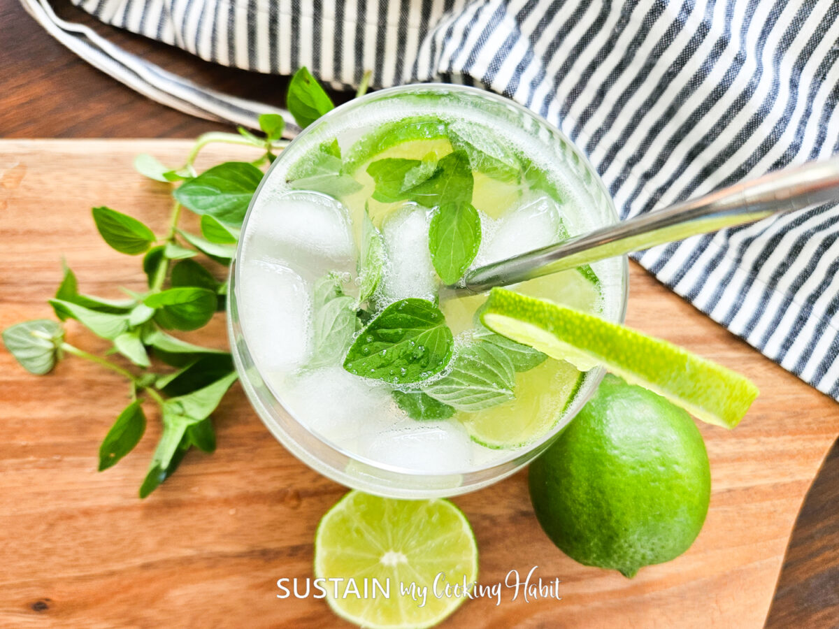 Overhead view of virgin mojito mocktail surrounded by limes and mint.