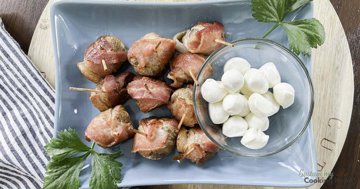 Overhead view of a bacon wrapped mushroom appetizer with garnish and mozzarella balls.