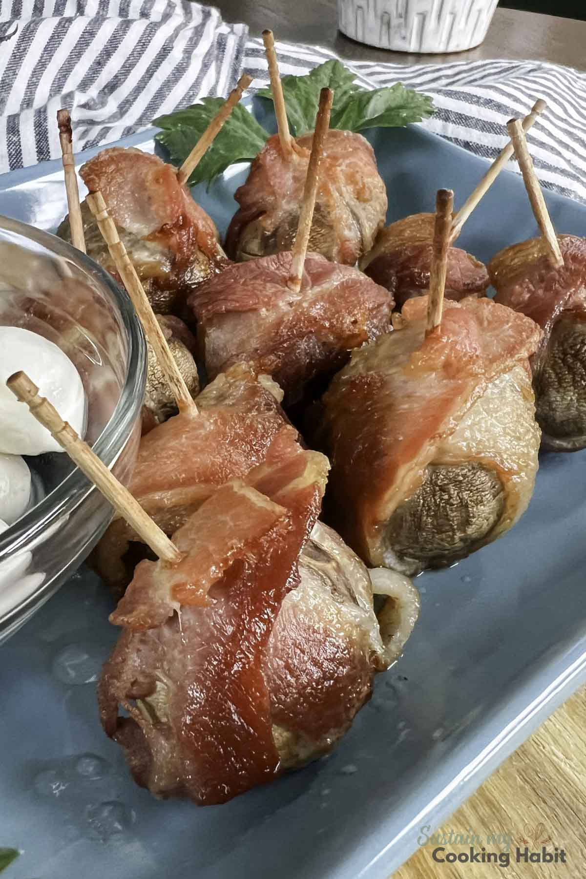 Bacon wrapped mushroom appetizer on a plate.